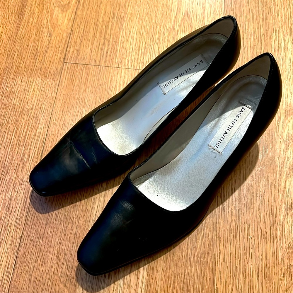These black leather pumps are branded by Saks Fifth Avenue.
